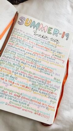 an open notebook sitting on top of a bed next to a book with writing on it