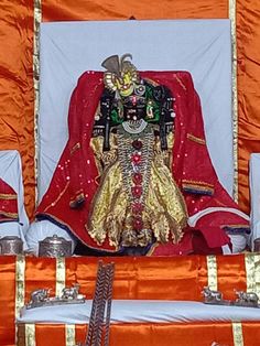 an elaborately decorated shrine with gold trimmings and red cloth on the floor