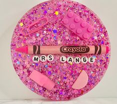 a close up of a pink glitter plate with crayons and lipstick on it