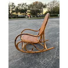 a wicker rocking chair sitting in the middle of a parking lot with no one around it