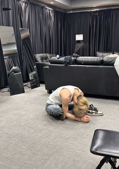 a woman kneeling on the floor in front of a black couch