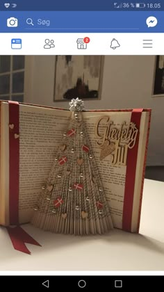 an open book with a christmas tree made out of folded books on top of it