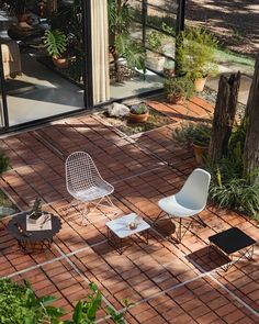 three white chairs sitting on top of a brick floor next to a table and chair