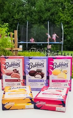 three boxes of bubble pops are sitting on a table in front of some children's play equipment