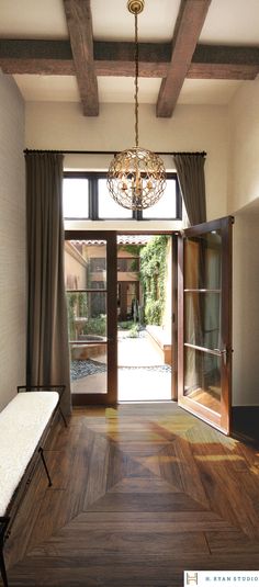 the inside of a house with wood floors and doors leading to a patio area that has a bench in front of it