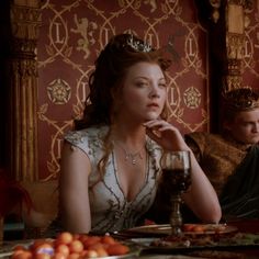 a woman sitting at a table in front of a man with a crown on his head