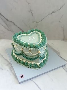 a heart shaped cake sitting on top of a white countertop next to a marble wall