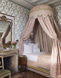 a canopy bed sitting in the middle of a bedroom next to a dresser and mirror