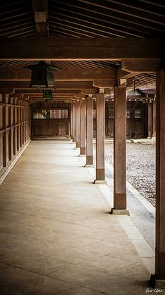 an empty building with columns and bells on the ceiling, in front of graveled ground