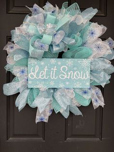 a wreath that says let it snow on the front door with blue and white bows