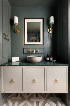 a bathroom vanity with marble counter top and gold fixtures