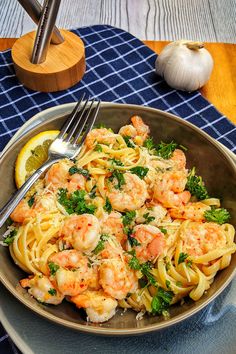 a bowl filled with pasta and shrimp on top of a blue table cloth next to garlic