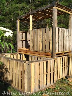 a wooden structure made out of pallet wood in the grass with trees behind it