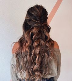 a woman with long, wavy hair is standing in front of a wall and has her back to the camera