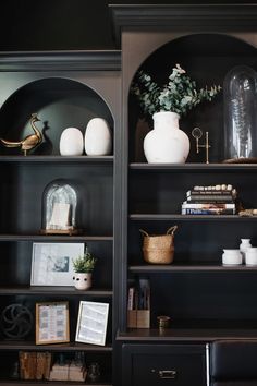 a black bookcase filled with books and vases