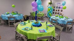 a room filled with tables covered in blue and green table cloths next to balloons