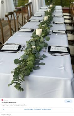 a long table is set up with place settings and greenery on it for an event