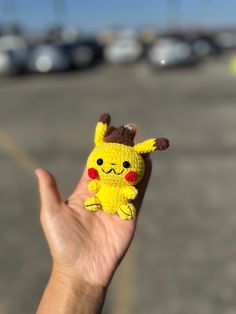 a hand holding a small yellow toy with a pikachu on it's finger