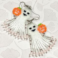 a pair of beaded ghost earrings sitting on top of a table