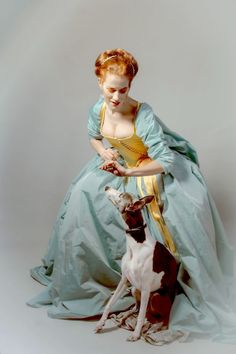 a woman in a blue dress is petting a dog