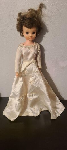 a doll is wearing a white dress and standing on a black table with her hair blowing in the wind