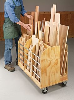 a man standing next to a cart filled with wooden boards and cutting board holders on wheels