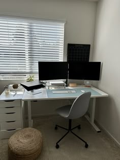 a desk with two computer monitors and a laptop on it in front of a window