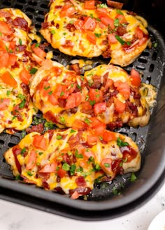 several mini pizzas with tomatoes and cheese on top in a black grilling pan