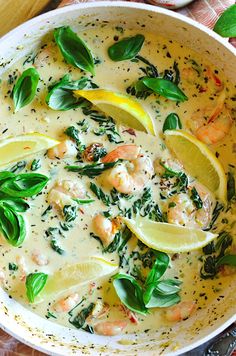 a bowl filled with shrimp, spinach and lemons