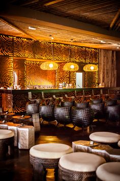 a room filled with lots of round tables and stools next to each other in front of a bar