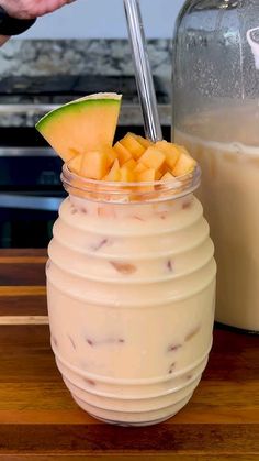 a person is holding a spoon over a drink in a glass with fruit on it