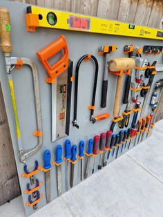 there are many tools hanging on the wall with each one's own tool holder