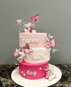 a three tiered cake with pink butterflies on top and happy birthday written on the side