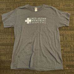 a gray shirt with the words greyson memorial hospital on it sitting on a brown carpet