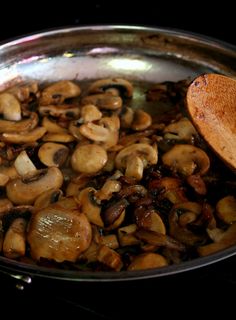 mushrooms cooking in a pan with a wooden spoon