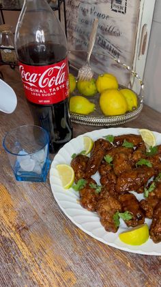 chicken wings with lemons and cilantro on a plate next to a bottle of coke