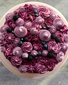 a cake decorated with purple icing and blackberries