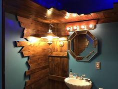 a bathroom with blue walls and wood paneling on the ceiling is lit by lights