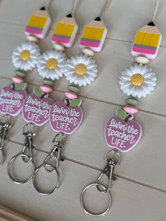 several teacher's life keychains with flowers and pencils on them