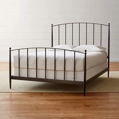 an iron bed frame with white sheets and pillows