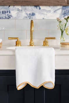 a gold faucet sits on top of a white towel in front of a sink