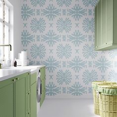 a bathroom with green cabinets and wallpaper in the shape of snowflakes