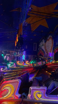 an amusement park filled with lots of rides and colorful lights in the dark night time