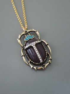 "Vintage Jewelry - Scarab Necklace - Vintage Inspired Necklace - Purple Necklace - Insect Necklace - Crystal Necklace - Gold Necklace This is such a cool vintage inspired necklace! An awesome antiqued gold scarab beetle bug is embellished with faux amethyst and turquoise and sparkling crystals. The pendant hangs from a gold plated rollo chain chain. Chloe says, Wear it and feel fabulous!\" The pendant is 1 1/2\" long. You can choose the chain length you would like at checkout. Thanks for visitin Scarab Necklace, Insect Necklace, Egyptian Revival Jewelry, Egypt Jewelry, Scarab Beetle, Beetle Bug, Necklace Purple, Egyptian Jewelry, Inspired Necklace