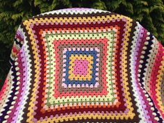 a colorful crocheted blanket sitting on top of a tree