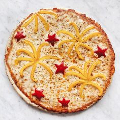 a pizza topped with orange slices and stars on top of a marble countertop next to a knife