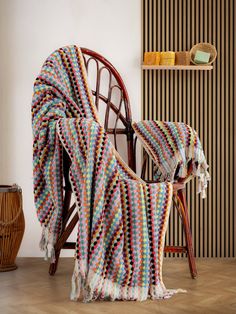 a chair with a blanket on top of it next to a wooden table and wall