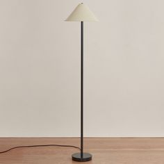 a floor lamp with a white shade on it's side and a black base