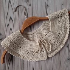 a crocheted sweater hanging on a wooden hanger