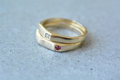 two gold wedding bands with pink sapphires on top and white diamond in the middle